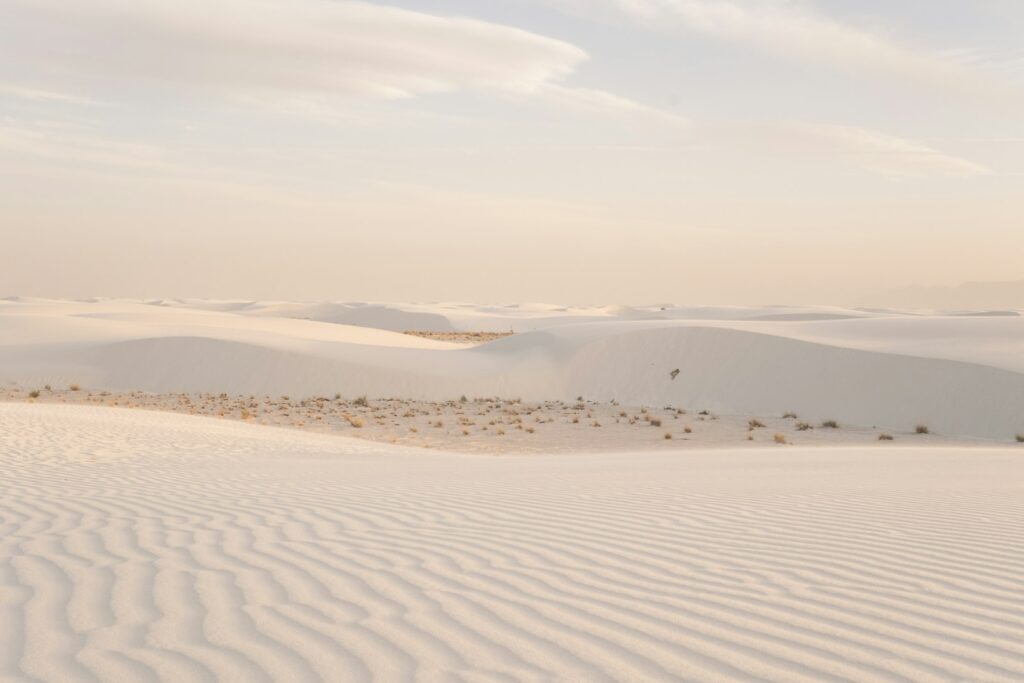 Expansive white sand dunes under a pale sky